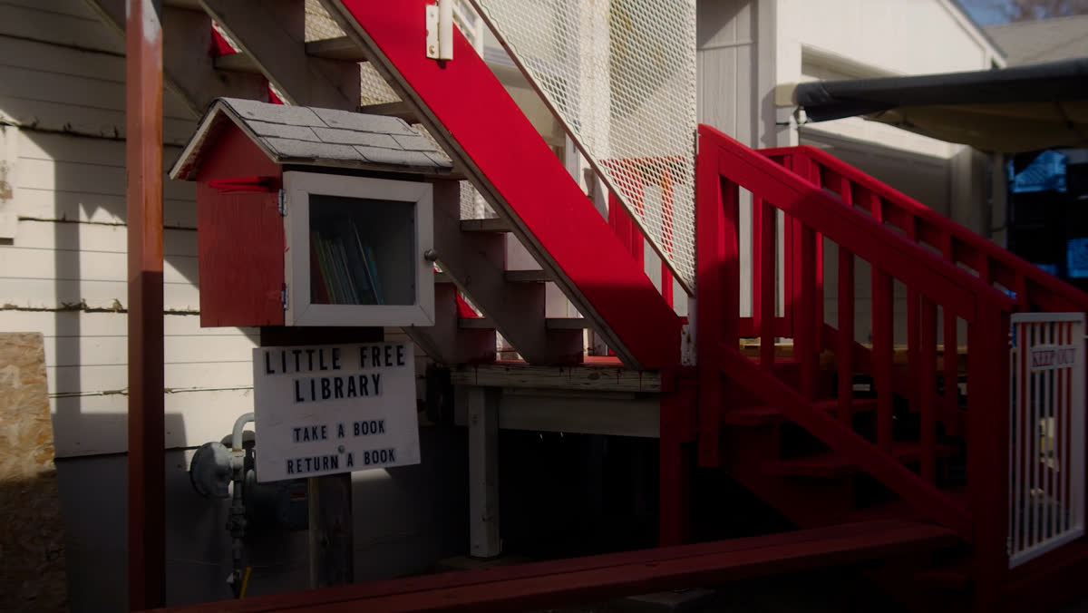 A little free library beside red stairs