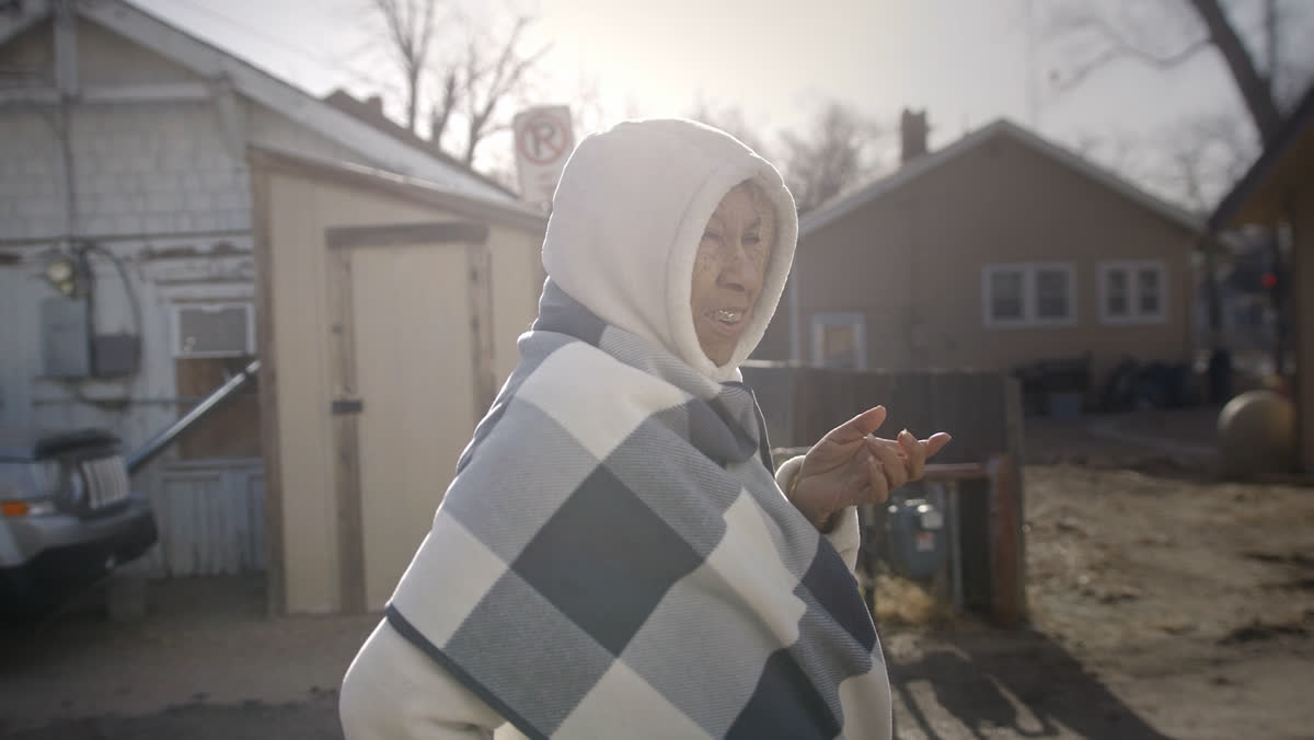 A woman wrapped in a blanket outside Emmaus House