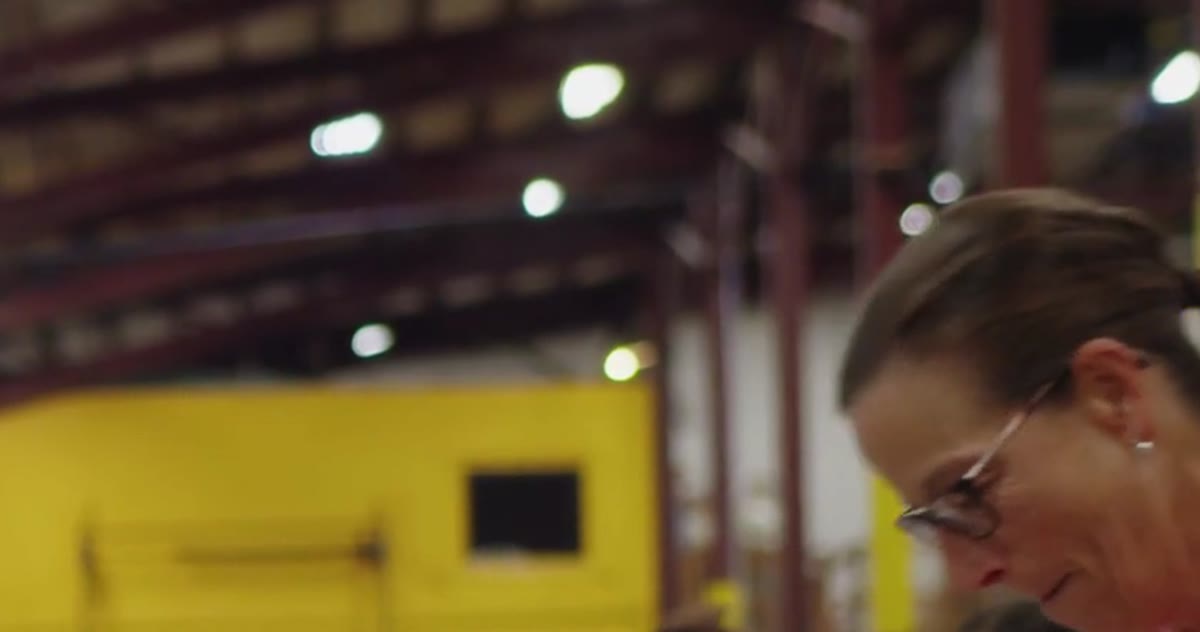 A volunteer sorts supplies under warehouse lights
