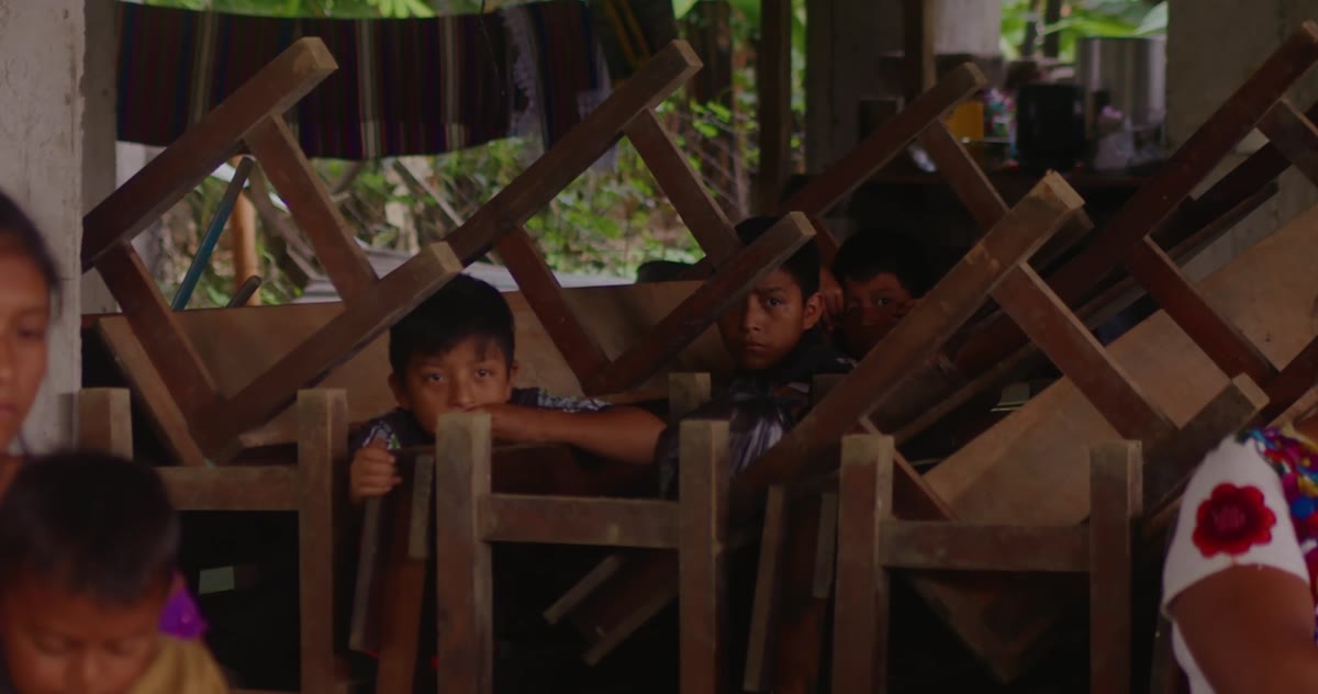 Children among stacked wooden chairs