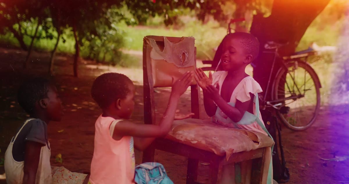 Children play beside a wooden chair at sunset